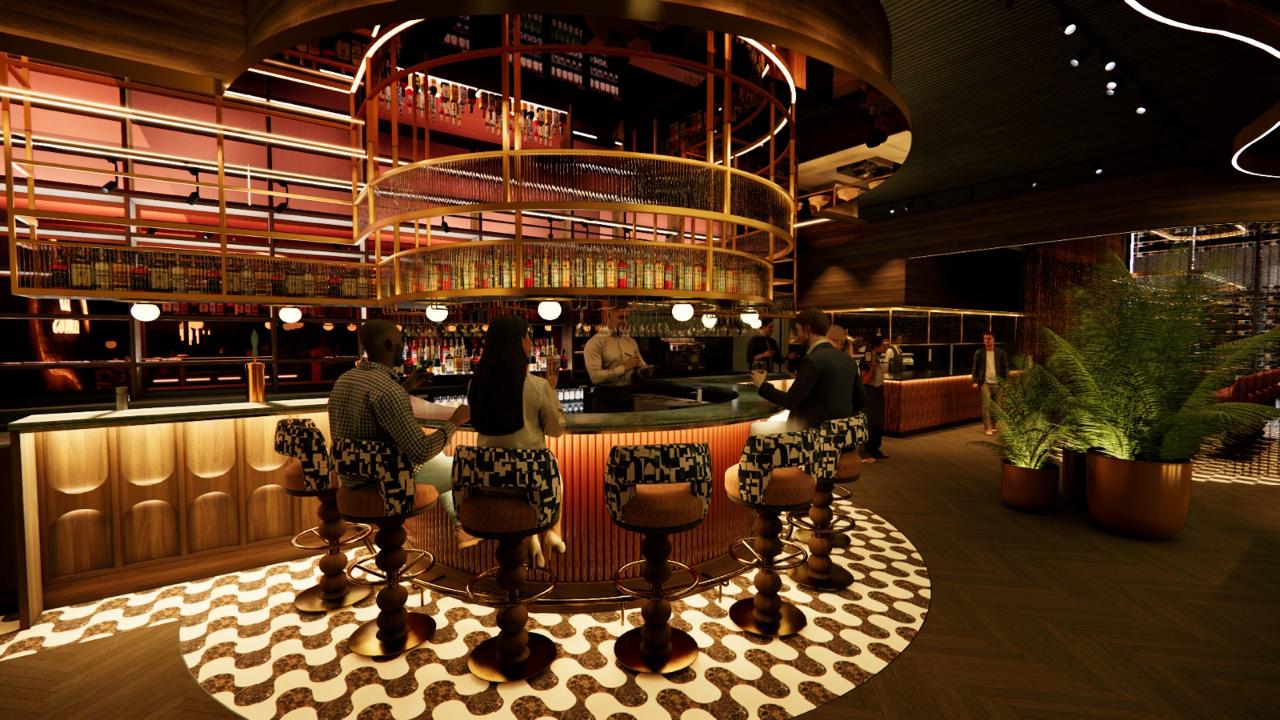 The double-height circular bar — a sculptural brass drinks tower rising through two floors, ringed by patterned bar stools.
